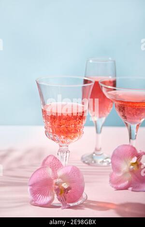 Cocktail rose tropical d'été dans un verre différent décoré de fleurs d'orchidées roses. Banque D'Images