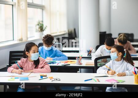 Divers élèves portant un masque facial gardant la distance sociale à l'école Banque D'Images