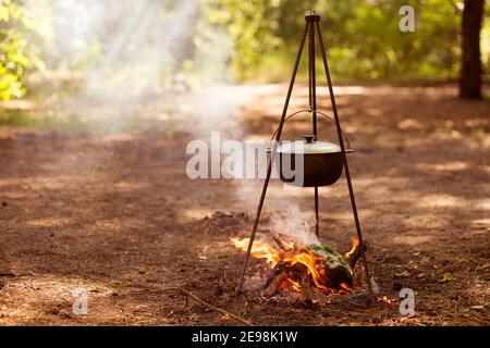 La nourriture est cuite au feu de camp dans la forêt. Voyages, tourisme, pique-nique en chaudron, feu et fumée. Banque D'Images