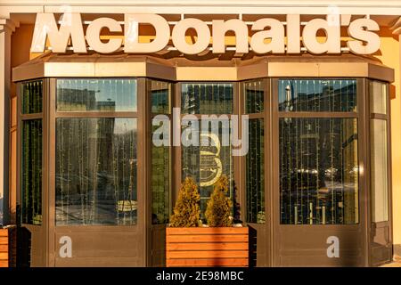 Minsk, Bélarus - 1er février 2021 : texte du panneau McDonald's et logo de la marque sur l'extérieur du restaurant de la restauration rapide McDonald's. Banque D'Images