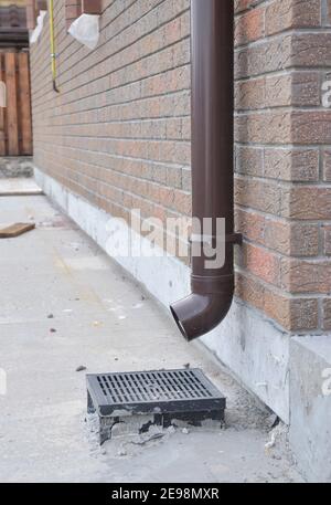 Installation du tuyau de descente de gouttière pour l'évacuation de l'eau de toit et le mur de fondation de la maison d'étanchéité. Systèmes de gouttières en plastique. Banque D'Images