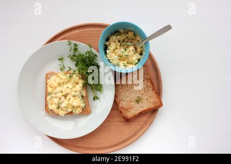 Sandwich à la salade d'œufs avec du pain grillé au blé entier et des micro-légumes sur plaque sur fond blanc. Concept d'alimentation saine Banque D'Images