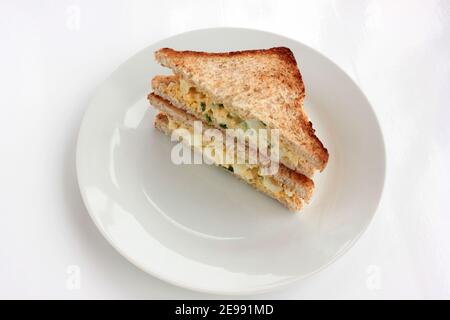 Sandwich à la salade d'œufs avec du pain grillé au blé entier et des micro-légumes sur plaque sur fond blanc. Concept d'alimentation saine Banque D'Images