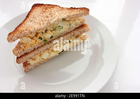 Sandwich à la salade d'œufs avec du pain grillé au blé entier et des micro-légumes sur plaque sur fond blanc. Concept d'alimentation saine Banque D'Images