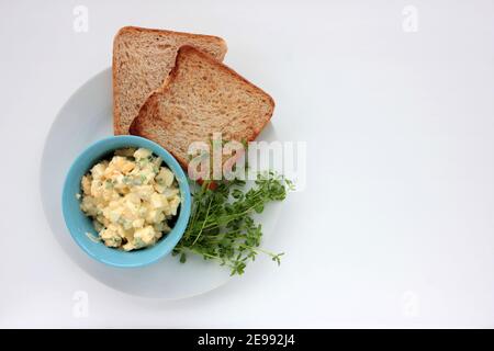 Sandwich à la salade d'œufs avec du pain grillé au blé entier et des micro-légumes sur plaque sur fond blanc. Concept d'alimentation saine Banque D'Images