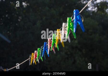 Rangée de clothpins colorés sur une corde à linge sur un noir arrière-plan Banque D'Images