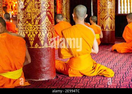 Luang Prabang, Laos Monks priant à l'intérieur de Wat Sibounheuang Banque D'Images