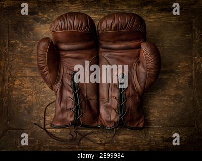 Paire de vieux gants de boxe en cuir marron couchés sur un table ancienne en bois Banque D'Images