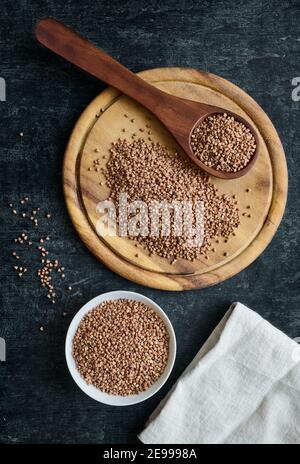 Sarrasin sur planche à découper, dans une cuillère en bois et un bol en céramique, grains anciens sans gluten pour une alimentation saine, plat Banque D'Images