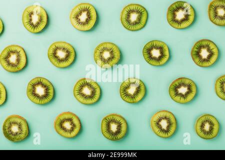Les motifs des tranches de kiwi sur fond vert comme fond continu. Fond de fruit conceptuel texturé Banque D'Images