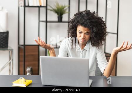 La jeune femme directrice de bureau afro-américaine, qui se sent stressée, fatiguée et surchargée, ne sait pas comment résoudre un problème, assis à son bureau Banque D'Images