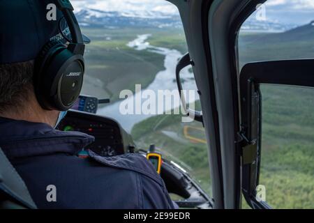 Gros plan d'un pilote d'hélicoptère dans un avion volant de cockpit Au-dessus des rivières Banque D'Images