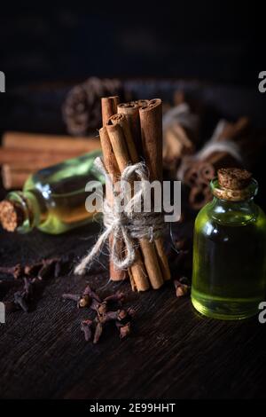 Sélection d'huiles essentielles avec bâtonnets de clou de girofle et de cannelle sur fond de bois. Banque D'Images