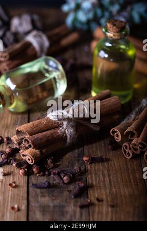 Sélection d'huiles essentielles avec bâtonnets de clou de girofle et de cannelle sur fond de bois. Banque D'Images