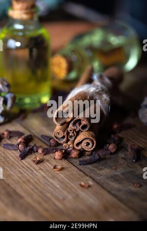 Sélection d'huiles essentielles avec bâtonnets de clou de girofle et de cannelle sur fond de bois. Banque D'Images
