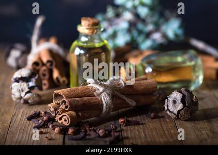 Sélection d'huiles essentielles avec bâtonnets de clou de girofle et de cannelle sur fond de bois. Banque D'Images