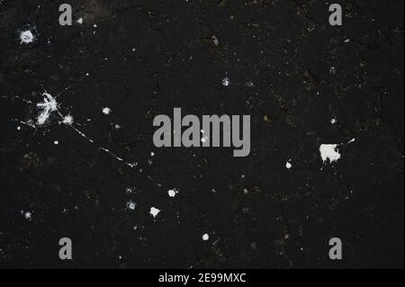 Des projections de peinture blanche renversées font des constellations sur de l'asphalte noir frais. Banque D'Images