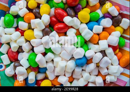 Bonbons de guimauve mélangés avec du sucre, bonbons en gelée de banane, fond avec bonbons, figurine de guimauve, anneaux de gelée Banque D'Images