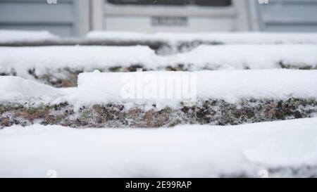 Gros plan sur un escalier extérieur en pierre en béton, avec une neige blanche couvrant chaque étape, montrant la profondeur de la neige de l'hiver. Banque D'Images