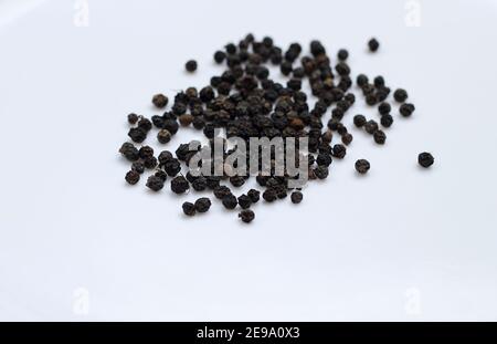 Peu de poivrons noirs sur fond blanc Banque D'Images