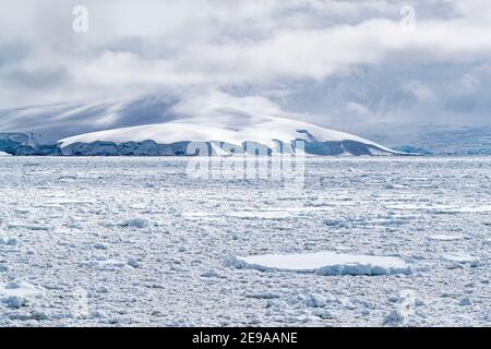 Montagnes enneigées et glace de mer dense dans le chenal Neumayer, l'archipel Palmer, l'Antarctique. Banque D'Images