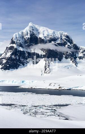 Montagnes enneigées et glace de mer dense dans le chenal Neumayer, l'archipel Palmer, l'Antarctique. Banque D'Images