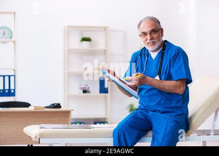 Médecin senior prenant des notes dans la clinique Banque D'Images