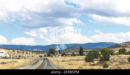 Feu dans la distance en Californie du Nord - conduite sur Route à 2 voies près de Susansville avec montagnes et fumée dans le distance - mise au point sélective Banque D'Images