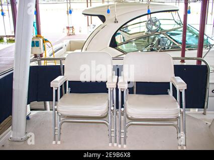 Au quai de Party - vue de deux chaises de bateau sur le pont arrière du croiseur amarré dans la marina avec un autre bateau dans le stalle à côté flou et lumières de fête han Banque D'Images