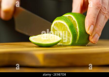 Femme coupant de la chaux dans la cuisine, de l'eau de citron, de l'eau rafraîchissante avec de la chaux et du citron, concept de saine alimentation Banque D'Images