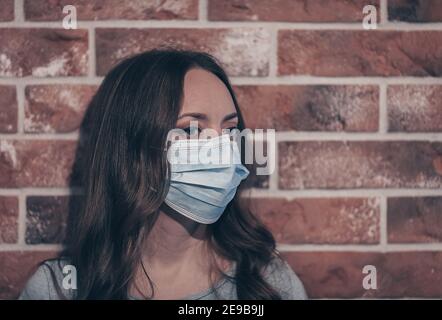 Femme portant un masque médical pour prévenir d'autres personnes de l'infection corona COVID-19 et du COV 2 du SRAS. Portrait d'une jeune femme portant un masque bleu, l Banque D'Images