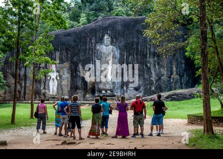 Les touristes admirent la statue de Bouddha sculptée de 15 mètres de haut à Buduruwagala. C'est la plus haute statue de Bouddha debout au Sri Lanka. Banque D'Images