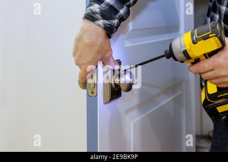 Maître avec tournevis installe accéder à la porte de la pièce nouvelle serrure dans la maison. Banque D'Images