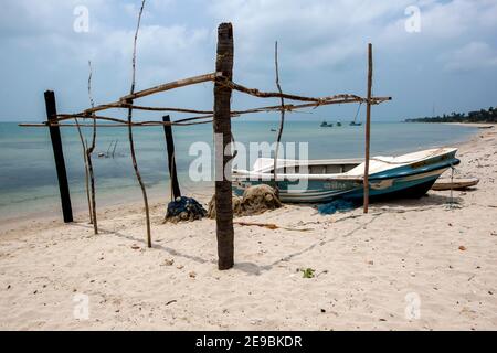 Un bateau de pêche se trouve à côté d'une cabane de pêche abandonnée sur une plage de l'île Delft, dans la région de Jaffna, au nord du Sri Lanka. Banque D'Images