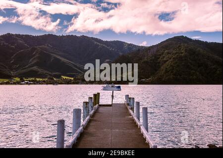 Groves Arm Jetty dans la baie de Momorangi, près de Picton, Nouvelle-Zélande. Vue le long de la vieille jetée en bois dans les Marlborough Sounds. Baie paisible, montagnes verdoyantes Banque D'Images