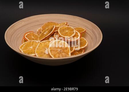 Gros plan sur des oranges séchées tranchées dans un bol en bois sur fond noir, espace de copie Banque D'Images