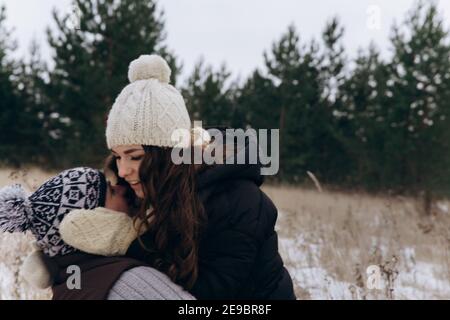 Un homme et une femme s'embrassent sur un fond de pins verts et de neige blanche Banque D'Images