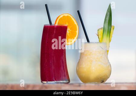 Cocktails fraîchement préparés avec des morceaux de fruits et des pailles noires sur une table en bois. Mise au point sélective et gros plan. Concept de loisirs et de style de vie. Banque D'Images