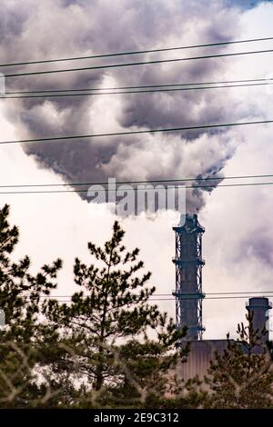 arbres en face de la fumée dense lourde de cheminée industrielle polluant le environnement Banque D'Images