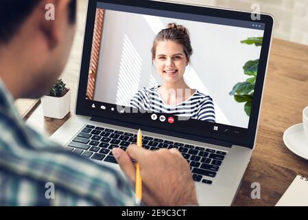 Jeune homme apprenant la langue étrangère avec une femme caucasienne via en ligne réunion par vidéoconférence sur ordinateur portable en période de pandémie Banque D'Images