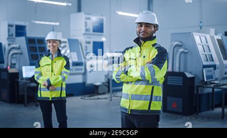 Portrait d'un magnifique ingénieur indien portant un gilet de sécurité et un casque de sécurité croise les bras et les sourices. Femme professionnelle travaillant dans la fabrication moderne Banque D'Images