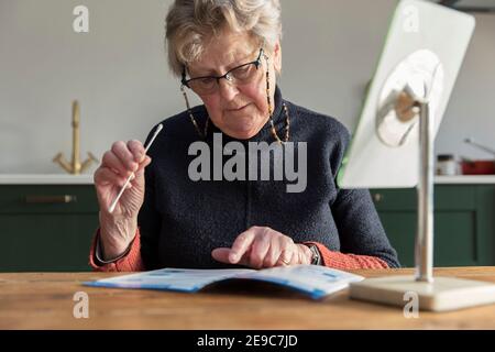 Une femme lit les instructions pour un coronavirus à la maison test par écouvillon Banque D'Images