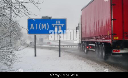 Camion passant le panneau de l'autoroute A1M dans la neige d'hiver Leeds Yorkshire Royaume-Uni Banque D'Images