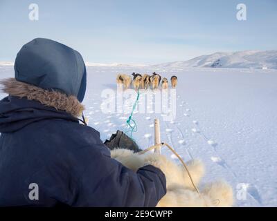 Chasseur inuit sur traîneau à chiens, portant des pantalons et des bottes traditionnels en fourrure d'ours polaire sur la glace de mer de la baie Melville, près de Kullorsuaq, dans le Nord Banque D'Images