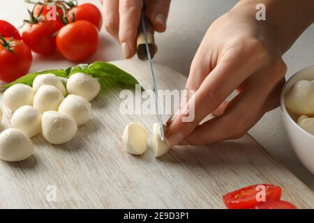 Femme qui coupe de la mozzarella sur la planche à découper, gros plan Banque D'Images