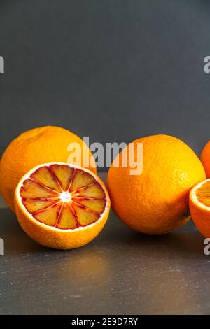 Des oranges de sang sur un fond sombre tapis d'ardoise, un en deux, portrait, espace de copie sur le dessus, macro gros plan. Banque D'Images
