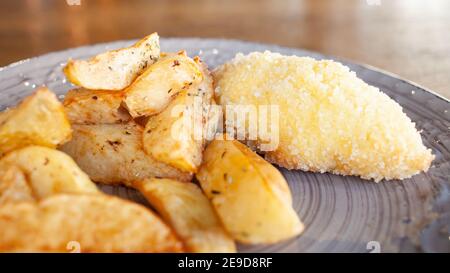 Pommes de terre cuites avec herbes et côtelettes en panure avec fromage et beurre. Nourriture sur une assiette en argile dans un café. Petit déjeuner, déjeuner et dîner au restaurant. Banque D'Images