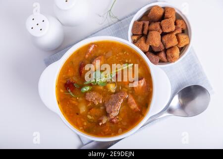 Soupe aux pois avec viande, saucisse fumée, pousses de pois et croûtons. Plat russe traditionnel. Cuisine maison. Gros plan, mise au point sélective. Banque D'Images
