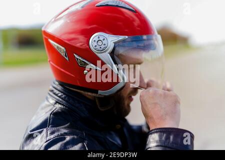 Jeune homme sportif mettant un casque de moto sur sa tête. Prêt pour une promenade. Banque D'Images