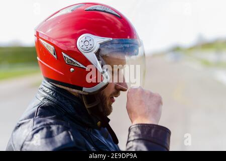 Jeune homme sportif mettant un casque de moto sur sa tête. Prêt pour une promenade. Banque D'Images